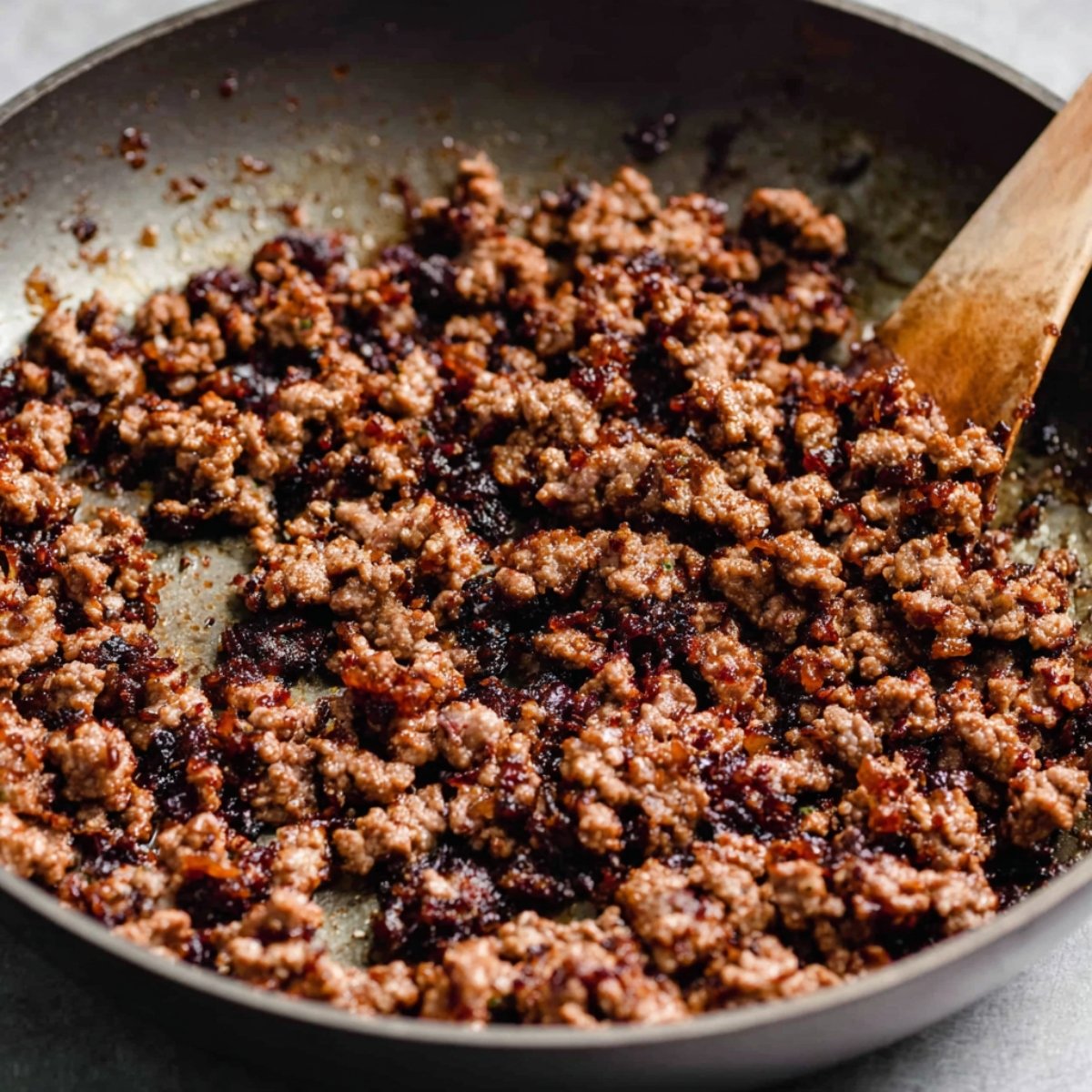 Ground beef browned in a skillet, with a crispy texture and browned bits on the bottom of the pan.