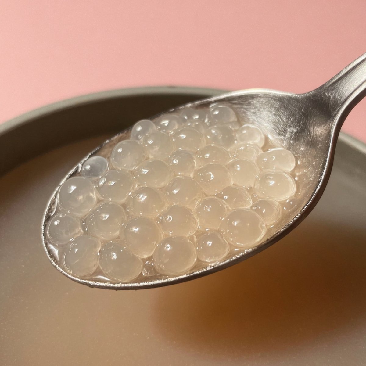 Close up of clear, chewy tapioca pearls glistening on a spoon, highlighting their perfect texture and shine.